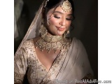 The image is a portrait of a beautiful Indian bride. She is wearing a traditional Indian bridal outfit with a white saree and...
