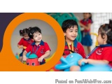 The image shows a group of children in a playroom. There are three children in the foreground, two boys and two girls, all we...