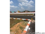 The image shows a construction site with a road in the foreground. The road is divided into two sections, with the left side...