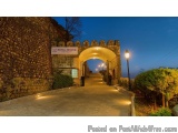 The image shows a stone archway with a sign that reads "Royal Orchid" at the top. The archway is located in a park or garden...