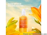 The image is an advertisement for a product called "Bloom Glaze Body Scrub Wash". The background is a bright blue sky with wh...