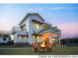 The image shows a beautiful two-story house with a modern design. The house is white with a red roof and has a balcony on the...