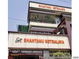 The image shows the exterior of a building named Shantanu Netralaya. The building is a two-story structure with a flat roof a...