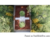 The image is an aerial view of a small square-shaped building surrounded by trees and bushes. The building appears to be made...