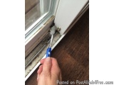 The image shows a hand holding a blue and white toothbrush with bristles. The toothbrush is being used to clean a window sill...