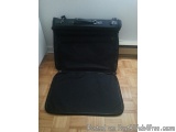 The image shows a black suitcase lying on a wooden floor. The suitcase appears to be made of a sturdy material and has a hand...