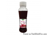 The image is of a bottle of red-colored liquid. The bottle has a white cap and a label with a red flower design on it. The la...