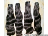 The image shows four bundles of hair extensions. The hair extensions are black in color and appear to be made of a loose, wav...