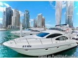 The image shows a white luxury yacht docked in a marina with tall buildings in the background. The yacht has the name "DT 117...