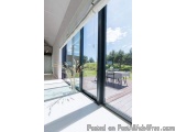 The image shows a modern and spacious room with a large sliding glass door that leads to a patio. The door is made of black g...