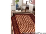 The image shows a living room with a large area rug in the center. The rug has a geometric pattern in shades of brown and bei...