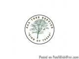 The image is a circular logo with a white background. In the center of the logo, there is a large tree with a green trunk and...