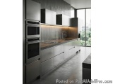The image shows a modern kitchen with a large window on the right side. The kitchen has a sleek and modern design with stainl...