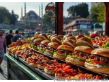 The image shows a long table with multiple trays of burgers and hot dogs on it. The trays are arranged in a neat row and are...