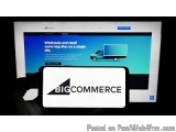 The image shows a person's hand holding a tablet with the logo of BigCommerce on the screen. The background of the screen is...