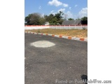 The image shows an empty parking lot with a white circle in the center. The parking lot is surrounded by a red and white stri...