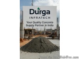 The image shows a construction site with a large pile of concrete in the foreground. In the background, there are several wor...