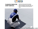 The image shows a man wearing a blue cap and overalls, kneeling on the floor and working on a tile installation. He is holdin...