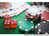 The image shows a pile of poker chips and playing cards on a green felt table. There are four red dices on the left side of t...