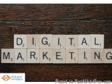 The image is a photograph of a wooden surface with the words "D2, D1, D2, Digital, Marketing" spelled out using Scrabble tile...