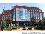 The image shows a modern building with a red brick exterior and large glass windows. The building is located on a street corn...