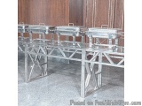 The image shows a long, rectangular table with four rectangular chafing dishes on it. The table is made of stainless steel an...