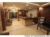 The image shows the interior of a hotel lobby. The lobby has a modern and luxurious design with a high ceiling and a chandeli...