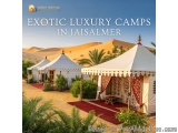 The image shows a group of luxury tents set up in a desert-like setting with sand dunes in the background. The tents are whit...