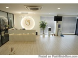 The image shows the interior of a modern office space with a large white reception desk in the center. The desk has a curved...