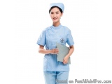 The image shows a young woman wearing a light blue nurse uniform. She is wearing a blue cap with a white logo on the left sid...