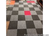 The image shows a large checkered floor in a store. The floor is made up of different shades of grey and black, with a red sq...