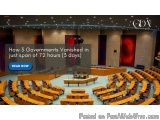 The image shows a large conference room with rows of wooden tables and chairs arranged in a semi-circle. The room has a high...