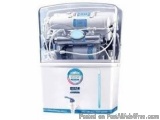The image shows a white-colored water purifier with a transparent cover. The cover is made of plastic and has a blue label on...