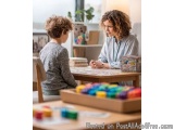 The image shows a mother and son sitting at a wooden table in a living room. The mother is sitting on the right side of the t...