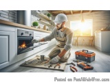 The image shows a man wearing a white hard hat and overalls, kneeling on the floor in front of a fireplace in a modern kitche...