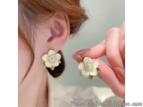 The image shows a close-up of a person's ear. The person is wearing a pair of earrings that are shaped like flowers. The earr...