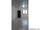 The image shows an empty room with white walls and a black door. The floor is made of light-colored tiles and the walls are p...