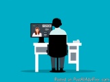 The image shows a person sitting at a desk in front of a computer monitor. The person is wearing a white shirt and black pant...