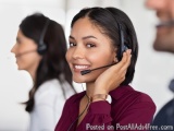 The image shows a young woman wearing a headset and smiling at the camera. She appears to be in a call center or a customer s...