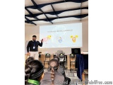 The image shows a man standing in front of a classroom full of students. He is giving a presentation on human intelligence to...