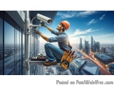 The image shows a construction worker on a high-rise building, installing a security camera on the side of the building. The...
