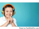 The image is a portrait of a young boy wearing orange and yellow headphones. He is wearing a white t-shirt and has a big smil...