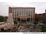 The image shows an aerial view of a large, modern building with a unique architectural design. The building is made of brick...