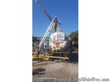 The image shows a construction site with a large white tanker truck parked on the ground. The truck has a crane attached to i...