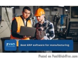 The image shows two men in a factory setting, both wearing orange hard hats and safety vests. The man on the left is holding...