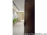 The image shows a modern and spacious hallway with a wooden door on the right side. The door is closed and the floor is made...