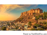 The image is a landscape photograph of a city at sunset. The sky is a beautiful orange and yellow color, with the sun setting...