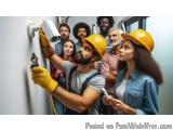 The image shows a group of people gathered around a security camera mounted on a wall. The security camera is white and has a...