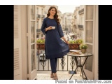 The image shows a young woman standing on a balcony with a view of a city street. She is wearing a blue kurta with a ruffled...