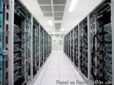 The image shows a long corridor in a data center. The corridor is lined with rows of servers, each with multiple rows of cabl...